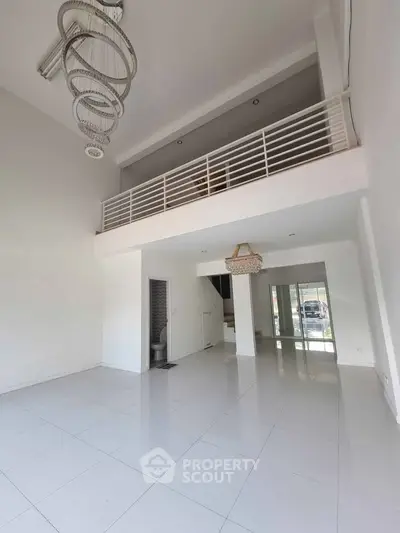 Spacious modern living room with high ceiling and mezzanine in a bright, open layout.