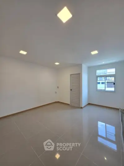Spacious empty room with glossy tiled floor and modern lighting, ideal for customization.