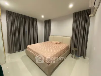 Spacious bedroom with elegant curtains and modern lighting, perfect for relaxation and comfort.