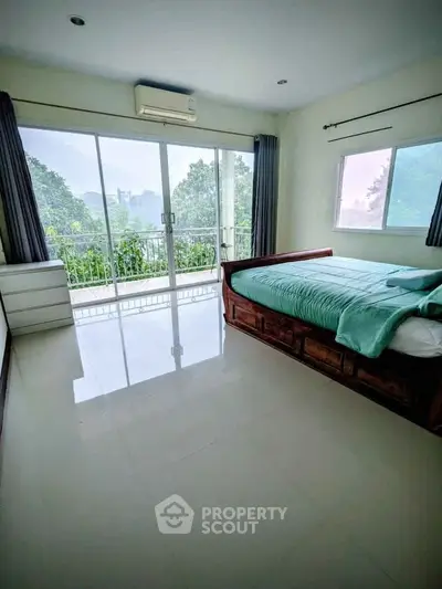 Spacious bedroom with large windows and balcony offering serene views.