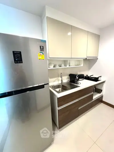 Modern compact kitchen with sleek cabinets and stainless steel fridge