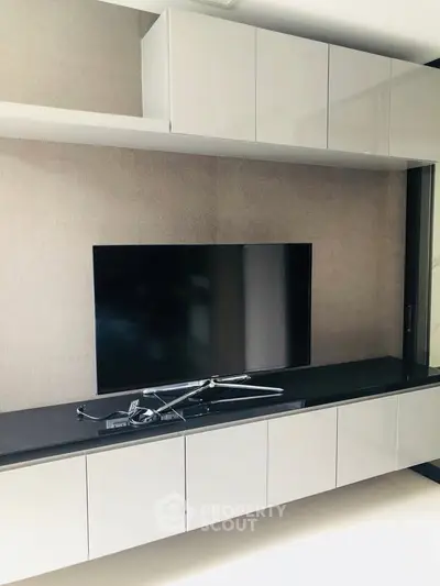 Modern living room with sleek built-in TV unit and glossy cabinets