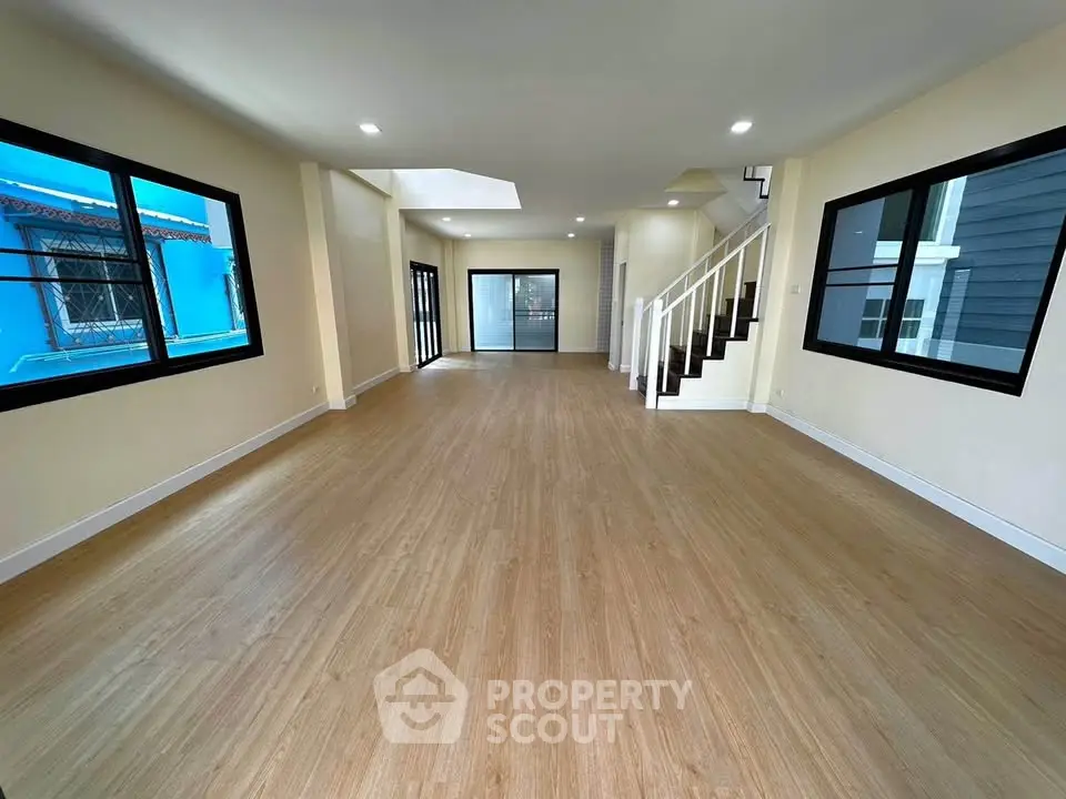 Spacious open-plan living room with modern staircase and large windows