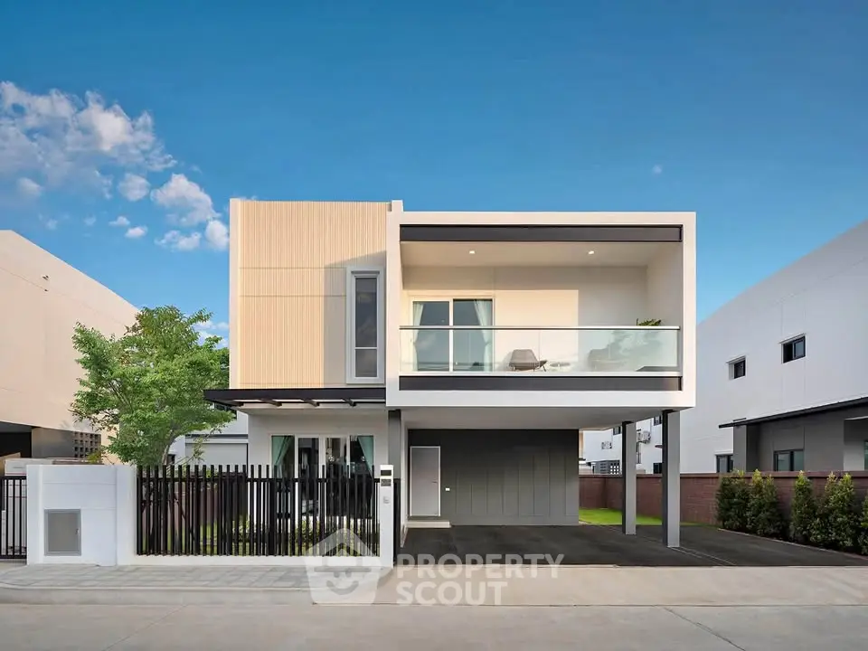 Modern two-story house with balcony and sleek design in a suburban neighborhood.