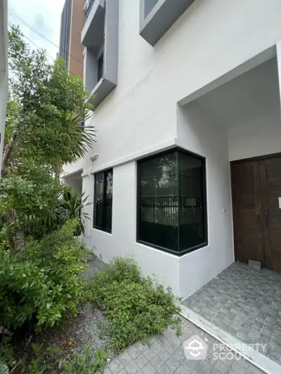 Modern townhouse exterior with lush greenery and stylish entrance