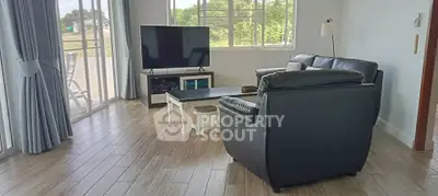 Spacious living room with modern leather furniture and large windows offering natural light.