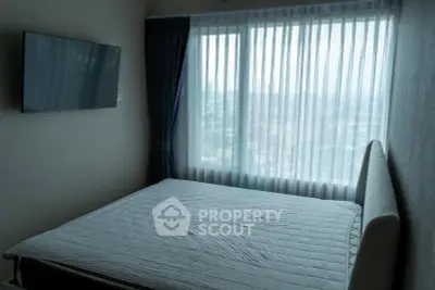 Modern bedroom with large window offering city view and wall-mounted TV.
