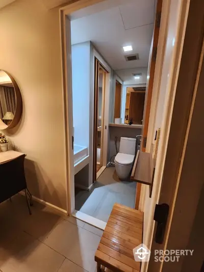 Inviting modern bathroom with sleek finishes, featuring a well-lit vanity area, large mirror, and a comfortable wooden bench, perfect for a relaxing retreat in a cozy home.