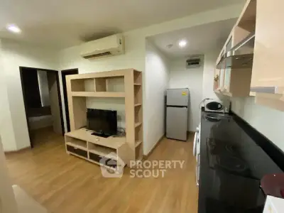 Modern apartment with open kitchen and cozy living area featuring wooden flooring and air conditioning.