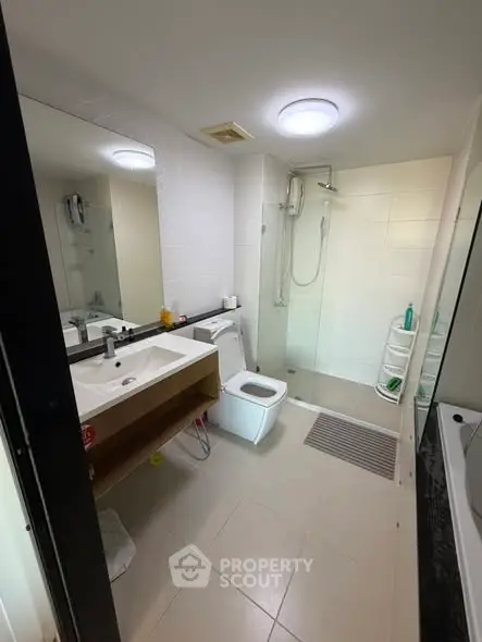 Modern bathroom with shower and sleek vanity in contemporary apartment.