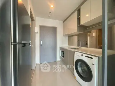 Modern kitchen with sleek appliances and washing machine in a compact layout.