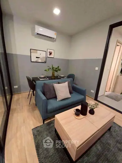 Modern living room with stylish decor and dining area, featuring a cozy blue sofa and elegant wooden table.