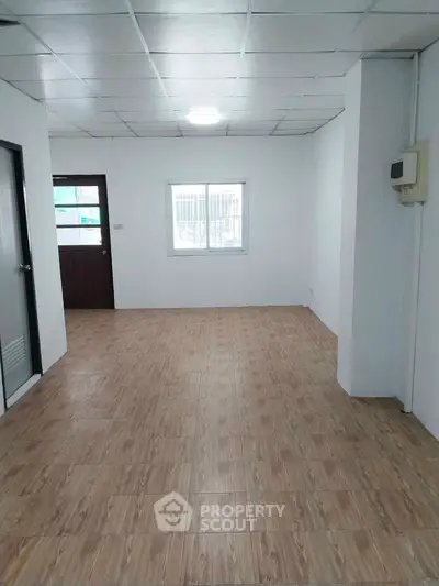 Spacious empty room with wooden flooring and bright natural light, ideal for customization.