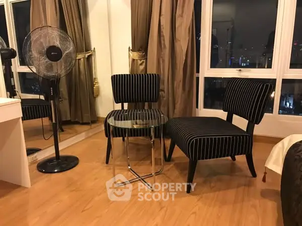 Cozy living room with stylish chairs and city view at night.