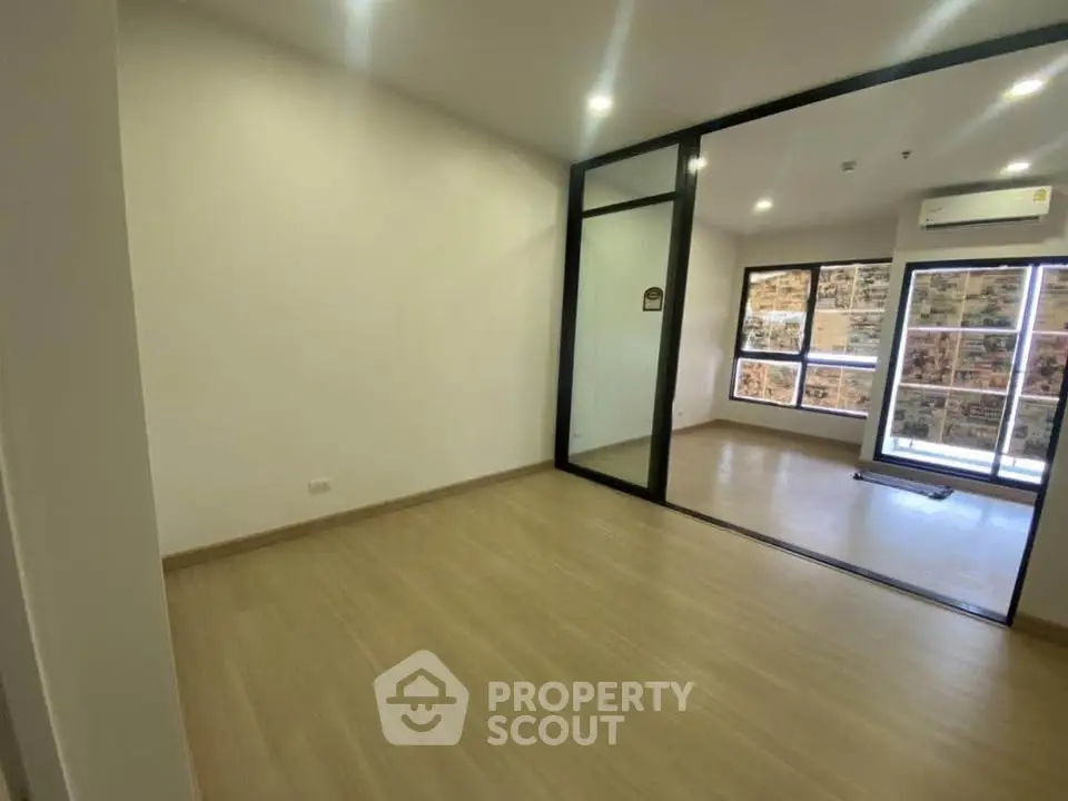 Spacious modern apartment with wooden flooring and large windows for natural light.