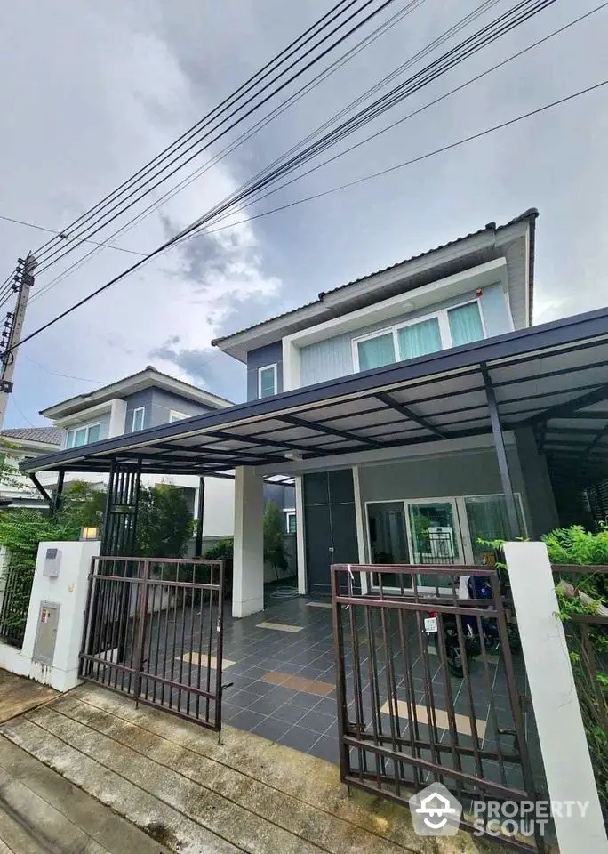 Modern two-story house with gated entrance and covered driveway in suburban neighborhood.