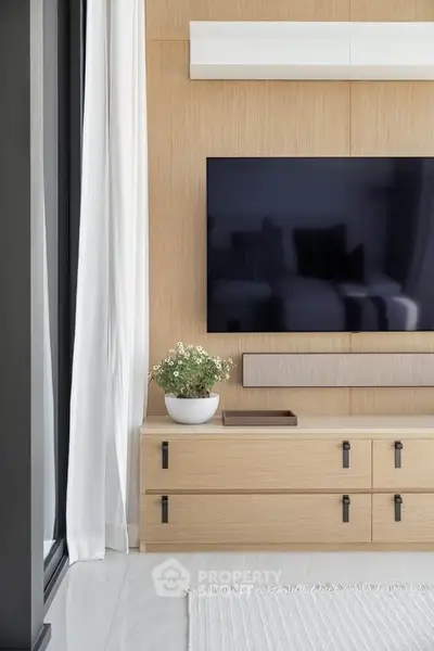 Modern living room with sleek TV setup and stylish wooden cabinetry.