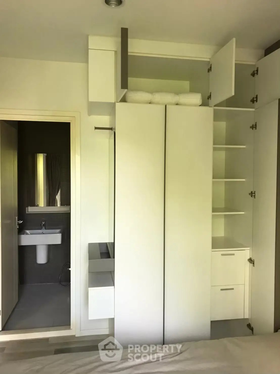 Modern bedroom with built-in storage and en-suite bathroom, featuring sleek white cabinetry and contemporary design.