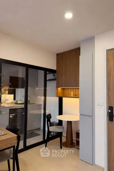 Modern kitchen with sleek design and open layout, featuring glass partition and stylish dining area.