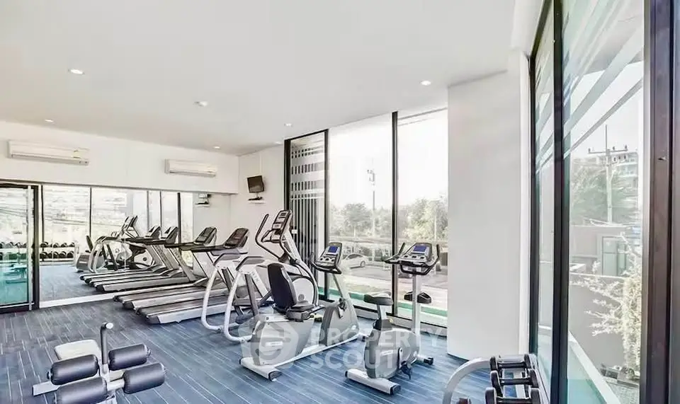 Modern gym with state-of-the-art equipment and large windows offering natural light.