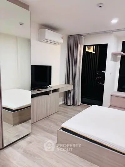 Modern bedroom with sleek design, featuring a mirrored wardrobe, wall-mounted TV, and large window for natural light.
