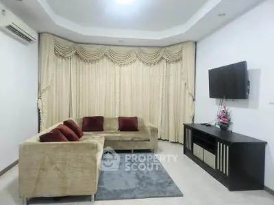 Elegant living room with plush sofa, wall-mounted TV, and stylish curtains.