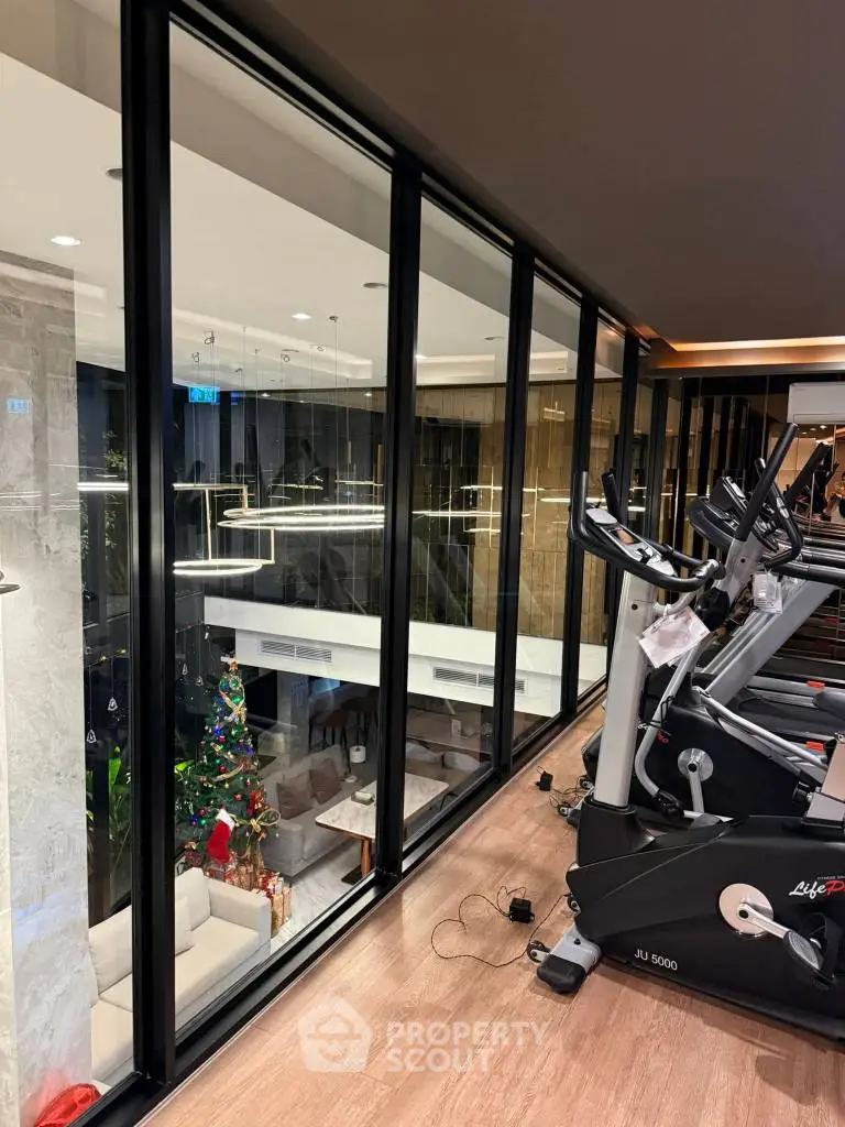 Modern gym with glass wall overlooking stylish living area and Christmas decor
