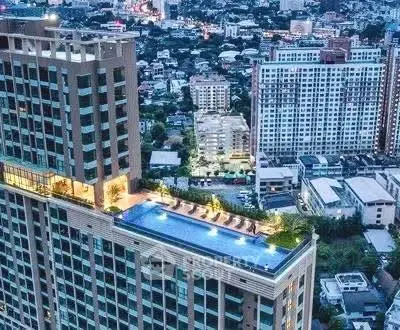 Stunning aerial view of luxury high-rise with rooftop pool in vibrant cityscape.