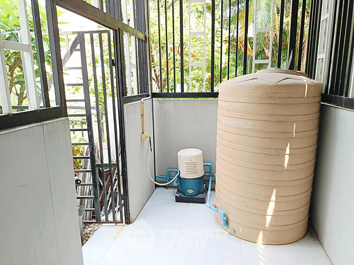 Outdoor utility area with water tank and pump in a modern home setting.