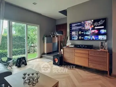 Stylish living room with modern decor and garden view, featuring a large TV and elegant wooden furniture.