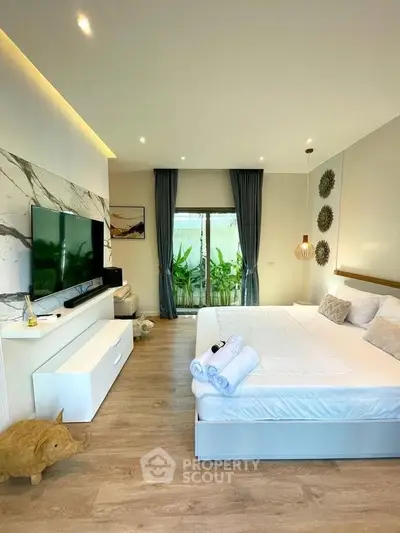 Luxurious bedroom with modern decor, large TV, and garden view, perfect for relaxation and comfort.