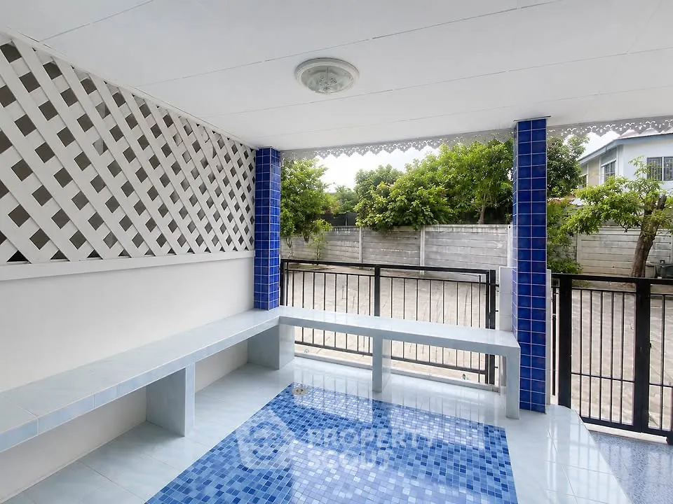 Charming outdoor patio with blue tile accents and garden view, perfect for relaxation and entertaining.