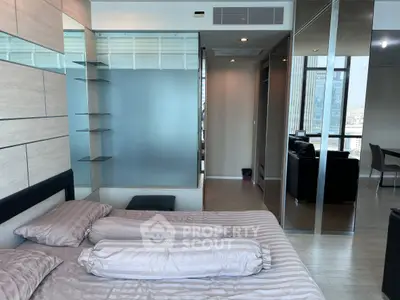 Modern bedroom with stylish decor and city view, featuring sleek glass partitions and elegant furnishings.