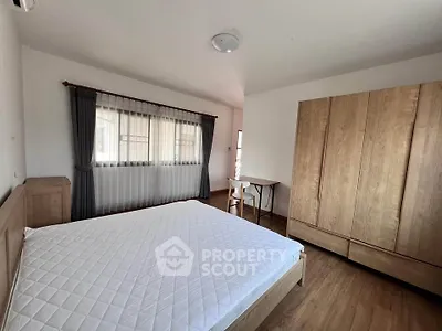 Spacious bedroom with wooden furniture and large window for natural light.