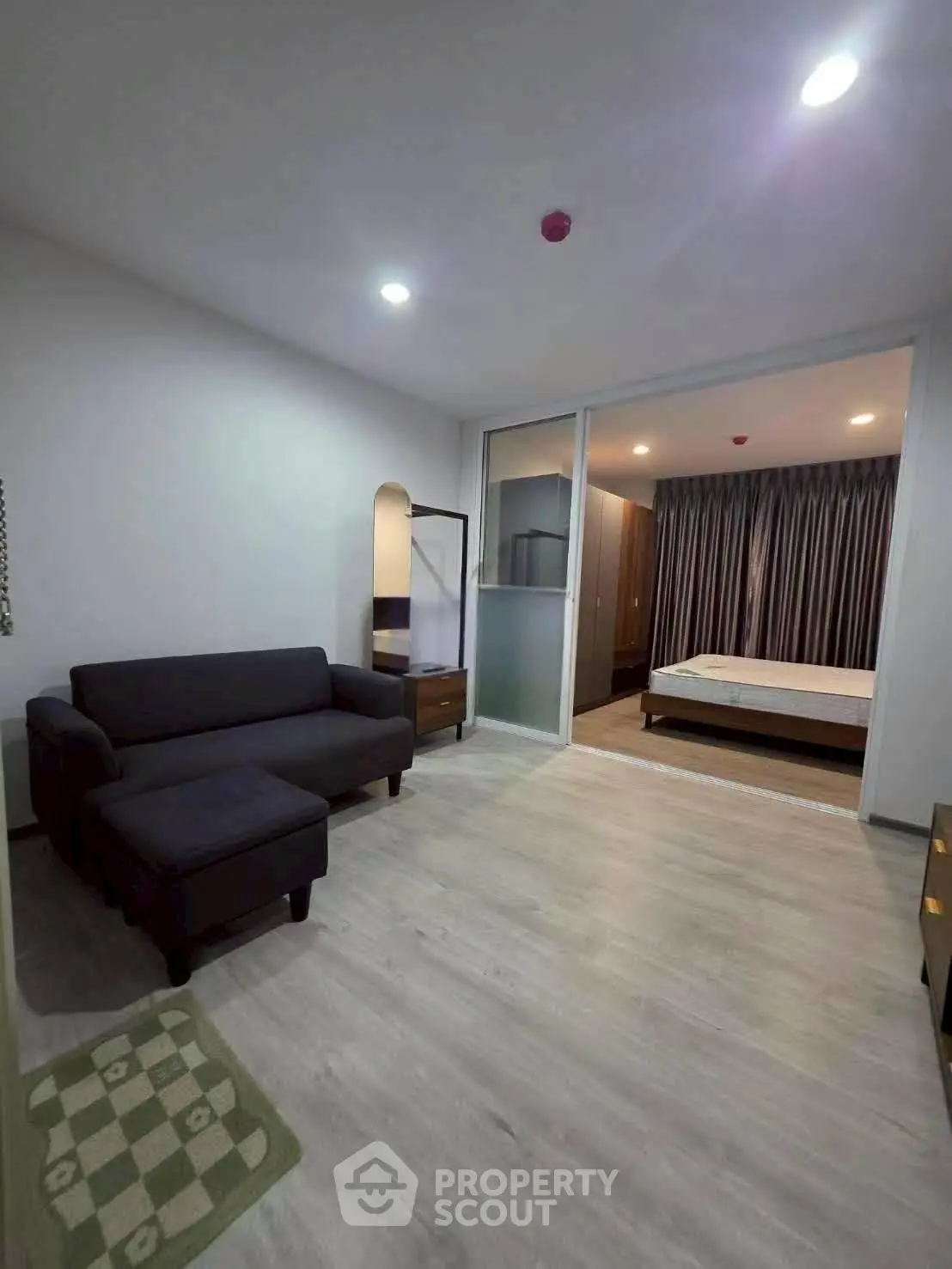 Modern apartment with cozy living room and spacious bedroom, featuring sleek furniture and ambient lighting.