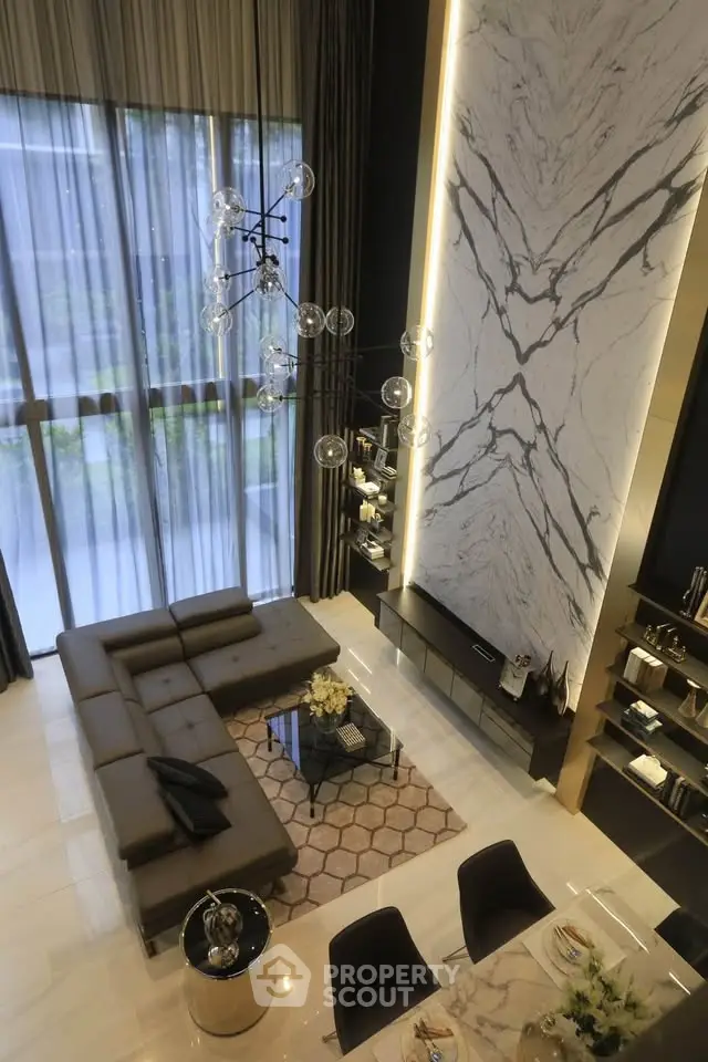 Luxurious modern living room with high ceilings, elegant marble wall, and stylish furniture.