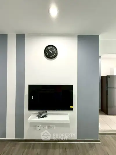 Modern living room with wall-mounted TV and stylish clock, featuring sleek design and contemporary decor.