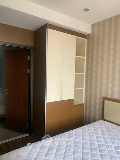 Cozy bedroom with modern wardrobe and stylish wallpaper, perfect for urban living.