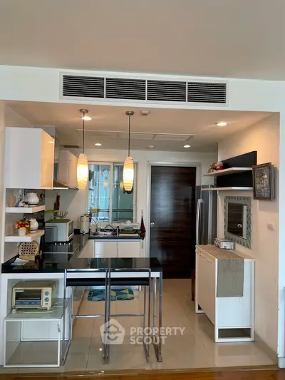 Modern kitchen with open layout, sleek appliances, and stylish lighting in a contemporary apartment.