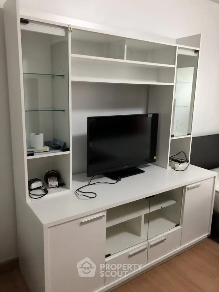 Modern white entertainment unit with TV and storage shelves in a stylish living room setup.
