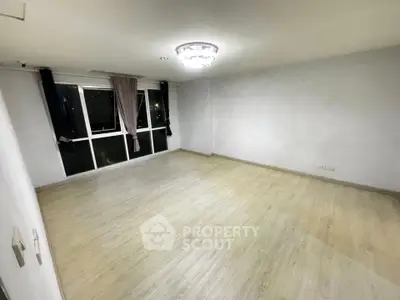 Spacious empty room with large windows and modern lighting, perfect for customization.