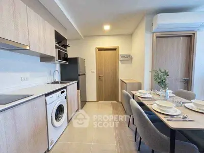 Modern kitchen with dining area, featuring washing machine and sleek appliances.