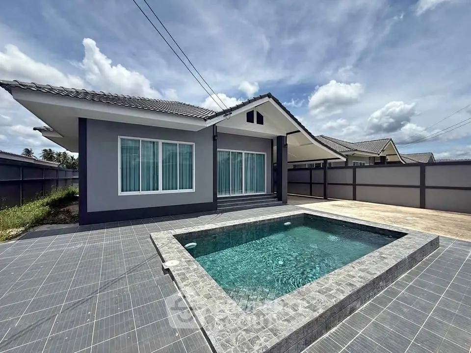Modern single-story house with private pool and spacious patio under a clear blue sky.