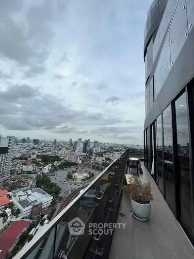 Stunning cityscape view from a modern high-rise balcony with glass railing and potted plants.