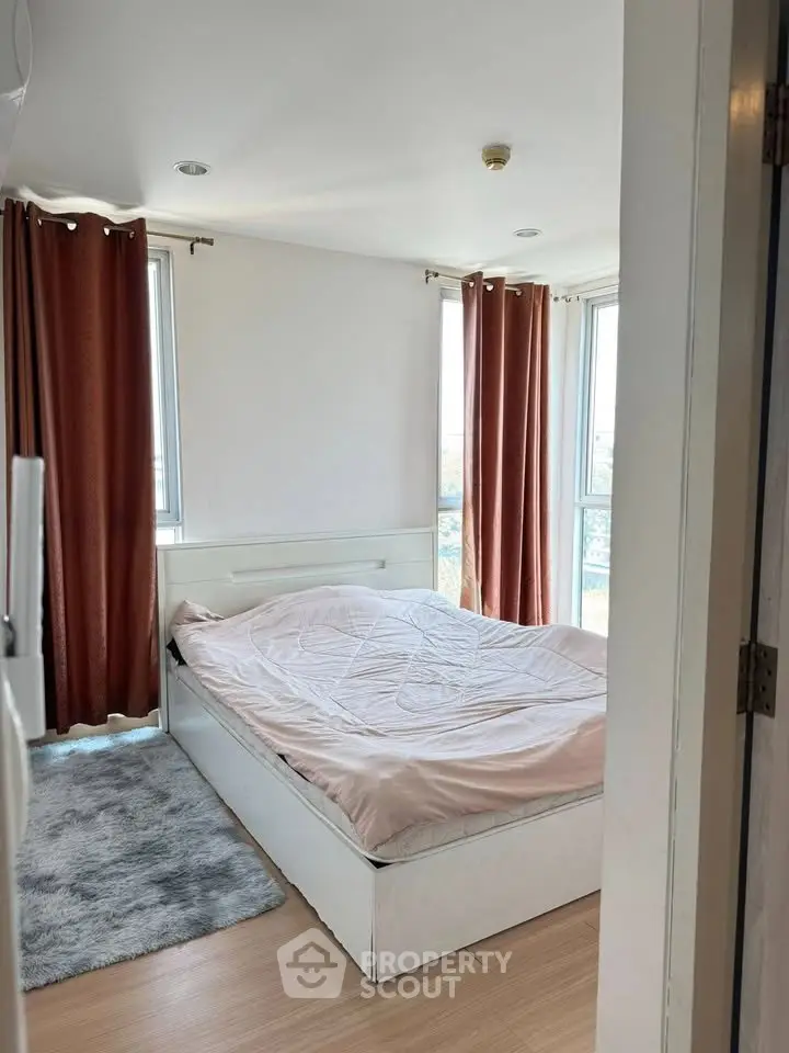 Cozy bedroom with large windows and modern decor in a high-rise apartment.