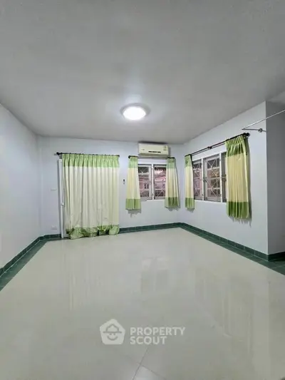Spacious unfurnished room with green curtains and air conditioning