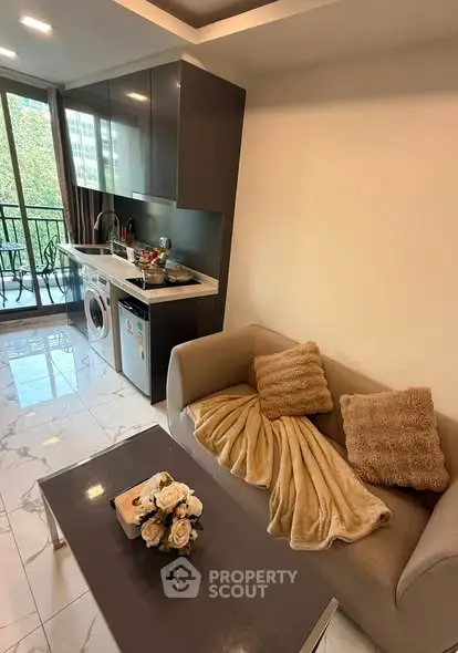 Modern apartment living room with open kitchen and balcony view, featuring cozy sofa and elegant decor.