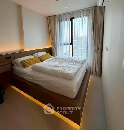 Modern bedroom with stylish lighting and city view, featuring a cozy bed and elegant curtains.