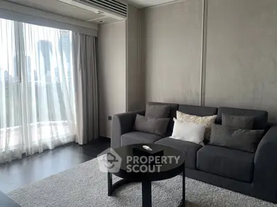 Modern living room with stylish gray sofa and city view through large windows.