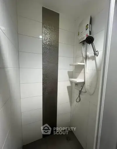 Modern bathroom shower area with sleek white tiles and water heater.